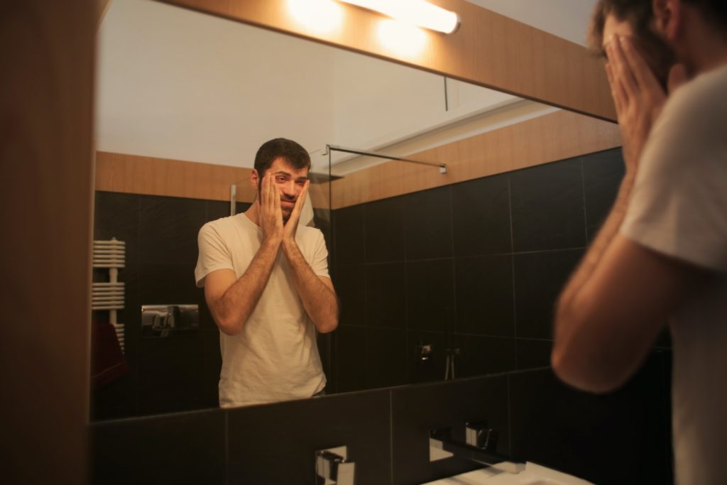 Tired man looking in mirror because he's bloated on keto.